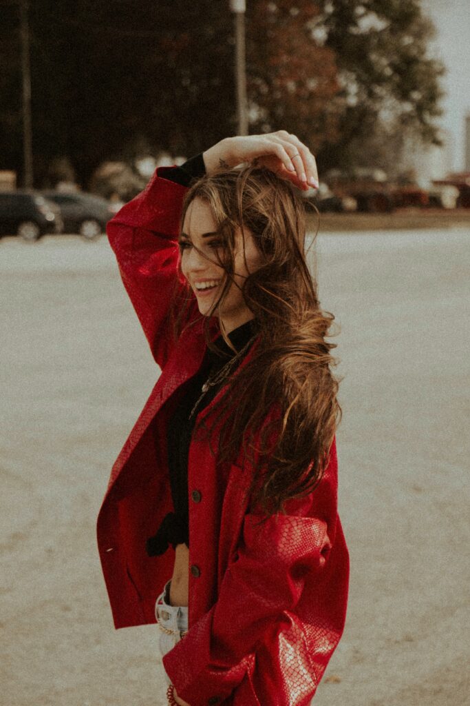 A brunette woman is on a bech with the wind blowing through the air.