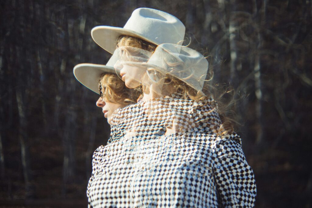 A multiple exposure film photo of a blonde woman with a hat looking out at the distance.